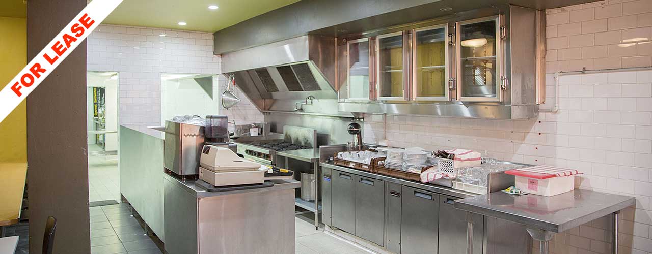 Commercial kitchen with stainless steel benches and extraction hood